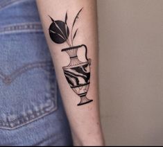 a black and white vase tattoo on the right arm, with a plant in it