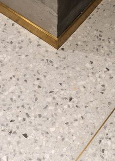 a marble floor with gold trim around the edges and a vase in the corner on the ground