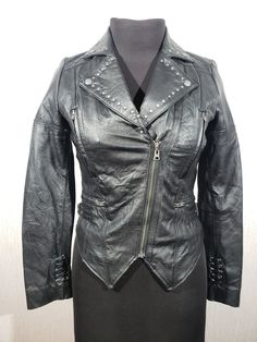 Cute women's leather jacket with a metal zipper. Women's black leather jacket. The jacket is made of durable black genuine leather. The jacket is easily fastened with a metal zipper. There are two pockets at the bottom of the jacket that close with a metal zipper and two at the top. The jacket has decorative rivets. The jacket has decorative laces on the sleeves and on the back. the cuffs of the jacket have metal snaps. The corners of the collar have metal snaps to which they can be fastened. On Leather Jacket With Rivets For Biker Events, Rocker Leather Biker Jacket With Rivets, Leather Jacket With Rivets, Leather Jacket With Rivets Long Sleeve, Leather Biker Jacket With Rivets, Black Leather Biker Jacket With Rivets, Punk Leather Jacket With Zipper Closure, Punk Leather Jacket With Zip Fly, Black Biker Leather Jacket With Metal Zipper