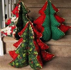 three christmas trees are sitting on the stairs