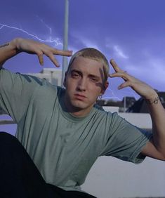 a man sitting on the ground with his hands in front of his face and lightning behind him