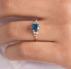 a woman's hand with a blue and white diamond ring on her left hand