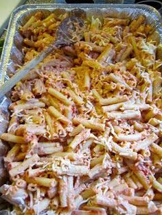 a pan filled with pasta and meat on top of a stove burner next to a spatula