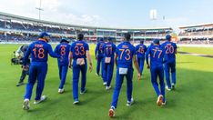 a group of men in blue uniforms walking across a field at a baseball game,