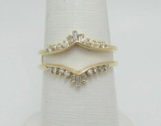 two gold rings with white stones on top of each other, sitting on a ring stand