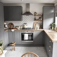 a kitchen with gray cabinets and wooden counter tops is pictured in this image, there are plants on the shelves next to the stove