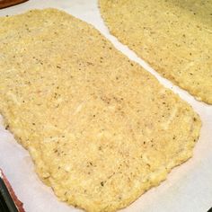 two uncooked pizza doughs sitting on top of a baking sheet