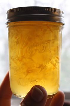 a person holding up a jar filled with liquid