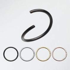 four pairs of black and gold nose rings with different colored metal hoops on white background