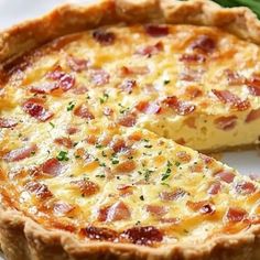 a quiche on a plate with a piece missing from the pie, ready to be eaten