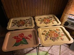 three trays with flowers painted on them sitting next to a toaster and oven