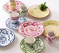 an assortment of colorful plates and cups on a table