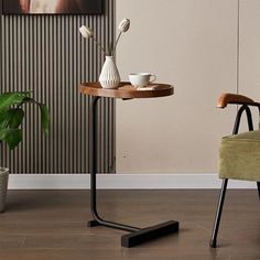 a small table with two cups on it next to a chair and potted plant