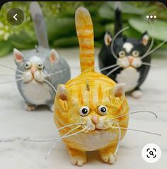 three cat figurines sitting on top of a white table next to each other