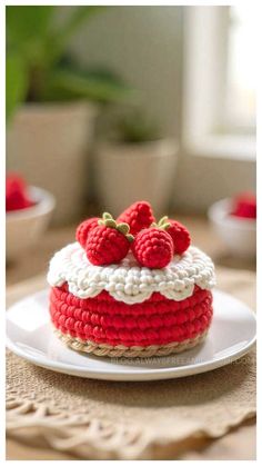 a crocheted cake with strawberries on top is sitting on a white plate