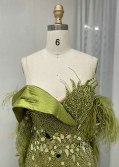 a mannequin wearing a green dress with feathers on it