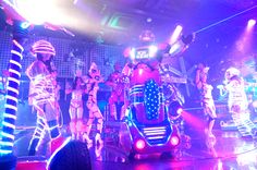 a group of people dressed up in costumes on stage with neon lights and disco balls