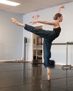 a woman is doing a ballet move in the middle of a dance studio with her legs spread out