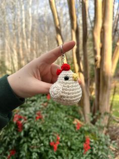 a hand holding a small crocheted keychain with a chicken on it