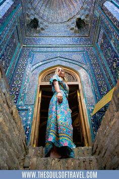 a woman standing in the doorway of an ornate building with blue and gold tiles on it