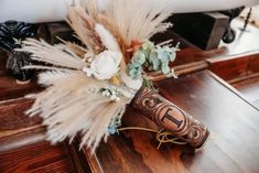 a vase filled with feathers and flowers on top of a wooden table