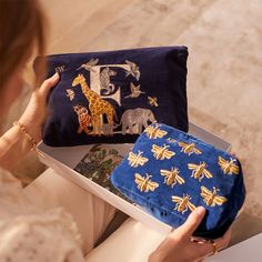 a woman is holding a blue purse with yellow bees on it and an elephant design