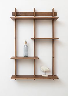 a wooden shelf with two bottles and a small bird on the top, against a white wall