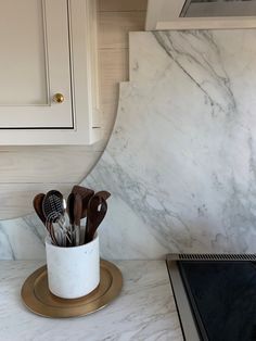 a marble kitchen counter top with utensils in a cup