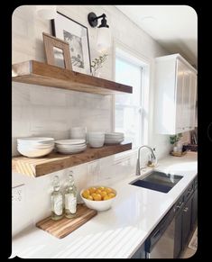 a kitchen with white counter tops and shelves filled with plates, bowls, and bottles