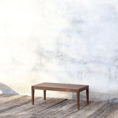 a small wooden table sitting on top of a wooden floor next to a white wall