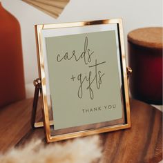 a sign that says cards and gifts is on a wooden table next to some candles