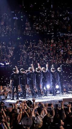 the backs perform on stage with their arms in the air as confetti is thrown around them