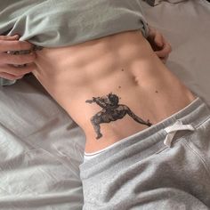 a person laying in bed with a tattoo on their stomach