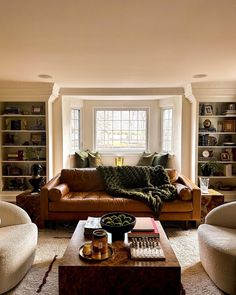 a living room filled with furniture and bookshelves in front of a large window