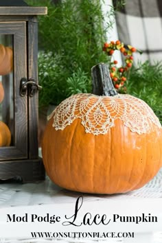 an orange pumpkin sitting on top of a table next to a lantern and potted plant