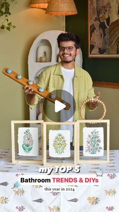 a man holding a wooden instrument in front of two pictures on a table with other items