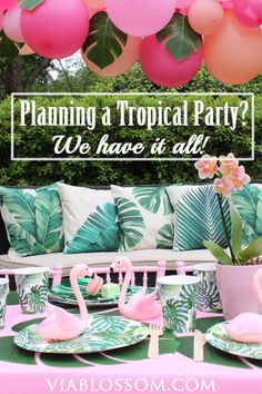 a tropical party with pink flamingos and green palm leaves on the table, balloons in the background