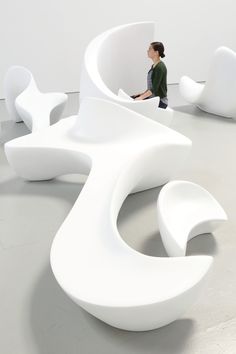 a woman sitting in the middle of a room with large white sculptures on the floor