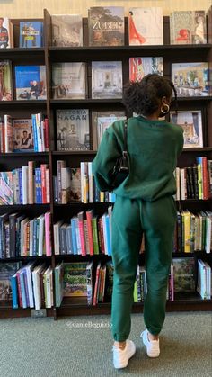 a woman standing in front of a book shelf filled with books