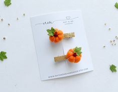 two small orange pumpkins with green leaves on them sitting on top of a card