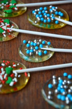 several spoons with candy on them are sitting on a table next to some lollipop sticks