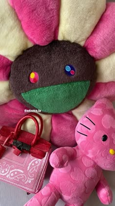 a pink teddy bear sitting on top of a bed next to a stuffed animal and purse