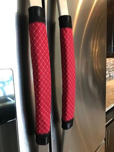 two oven mitts on the handle of a stainless steel refrigerator