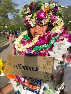 a woman in a lei and flower headdress holding a sign that says lamaamalie