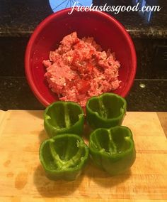 three green peppers sitting on top of a wooden cutting board next to a red bowl filled with meat