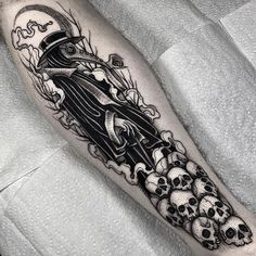 a black and white tattoo on the leg of a man with skulls around him,