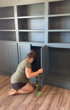 a woman kneeling on the floor with a bottle in front of some bookshelves