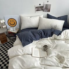 an unmade bed with white sheets and blue pillow cases on the bottom, next to a black and white checkered floor