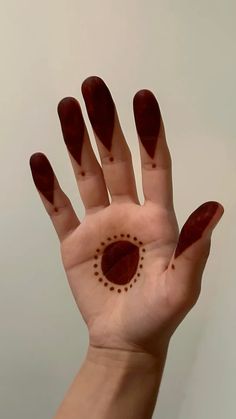 a person's hand with red nail polish on it and a circle drawn on the palm