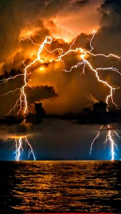 lightning striking over the ocean at night with clouds in the background and water below it